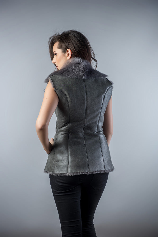 Woman wearing a gray leather vest with fur collar on a gray background