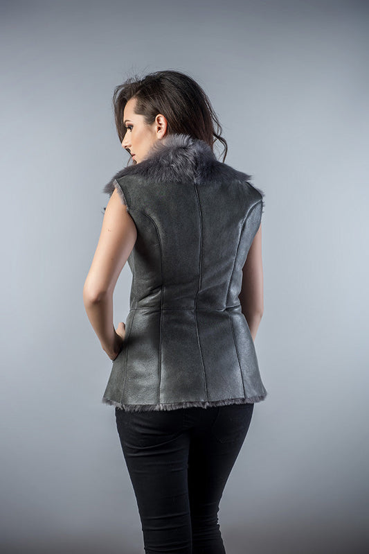 Woman wearing a gray leather vest with fur collar on a gray background