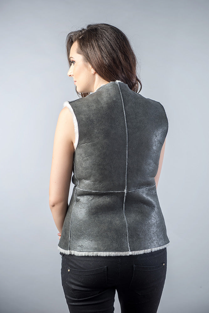 Woman wearing a gray leather vest against a plain background