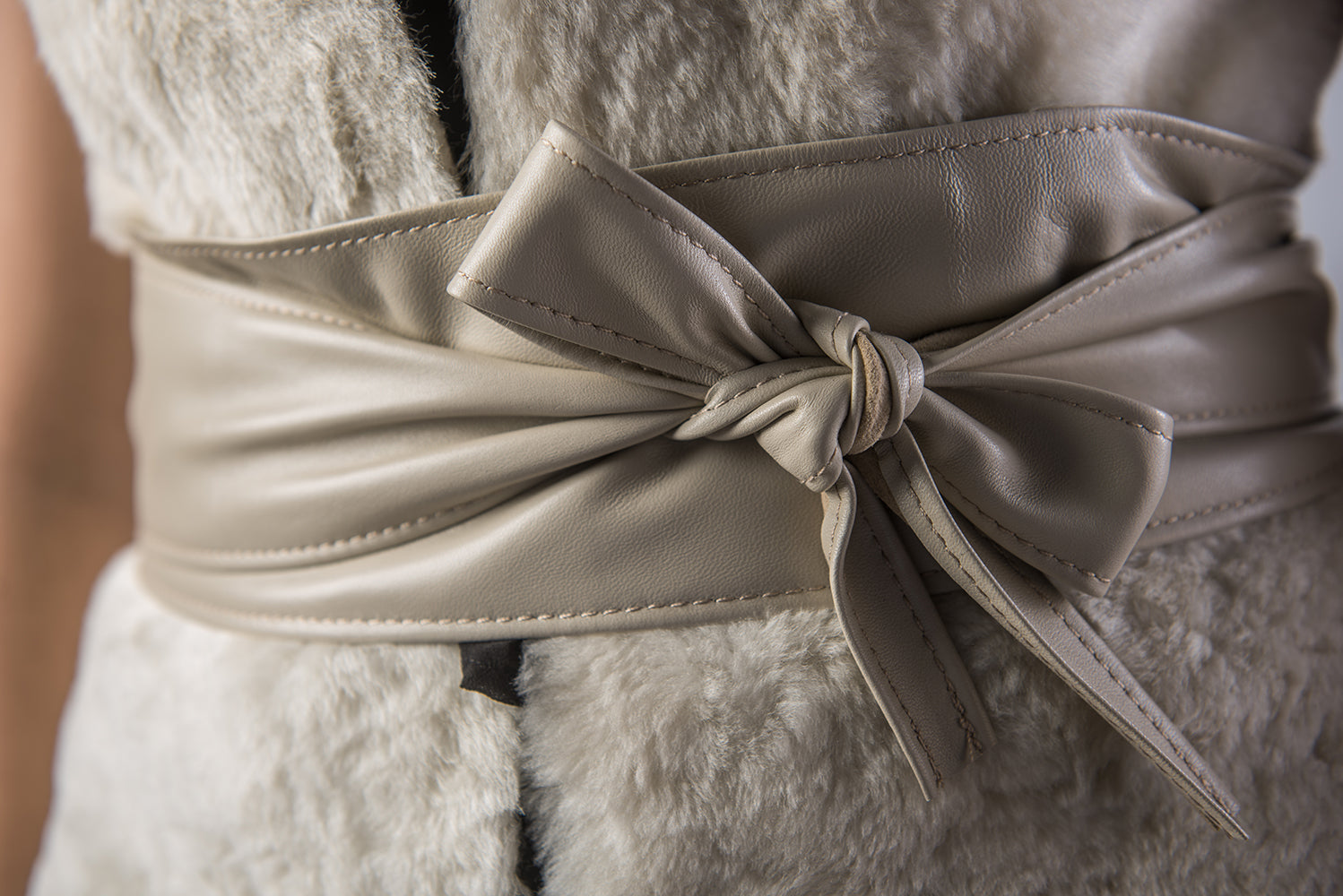 Close-up of a beige belt with a bow on a textured fabric background