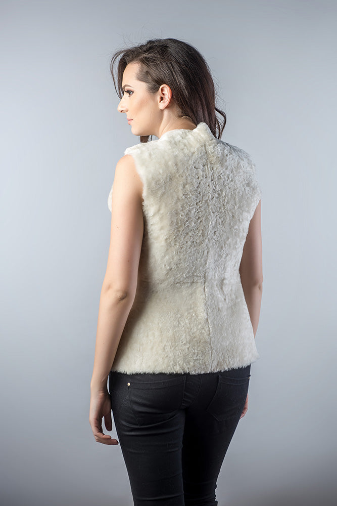 Woman wearing a white fur vest against a gray background