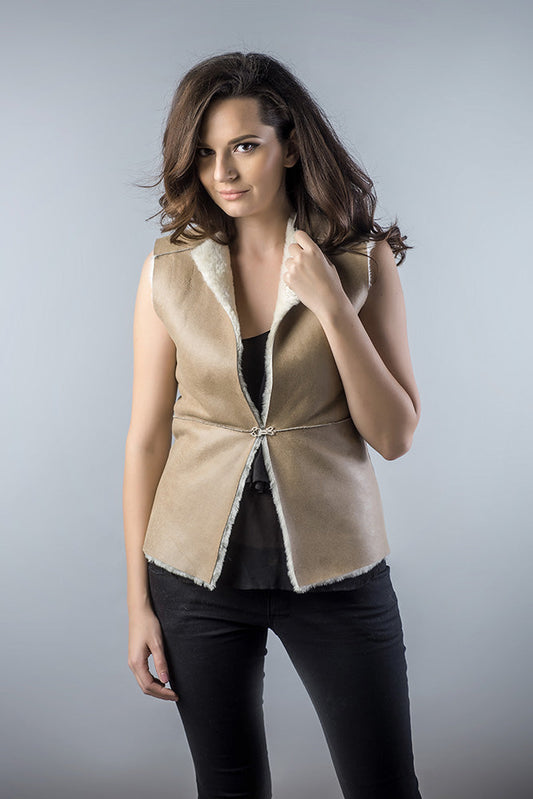 Woman wearing a beige vest with a plain background
