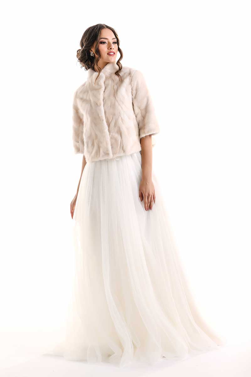 Woman wearing a beige jacket over a white dress on a white background