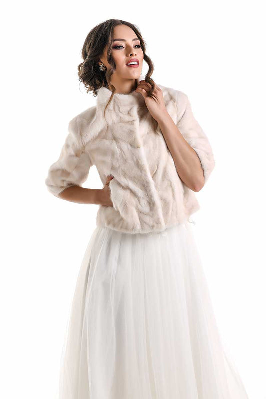 Woman wearing a beige fur jacket over a white dress on a white background