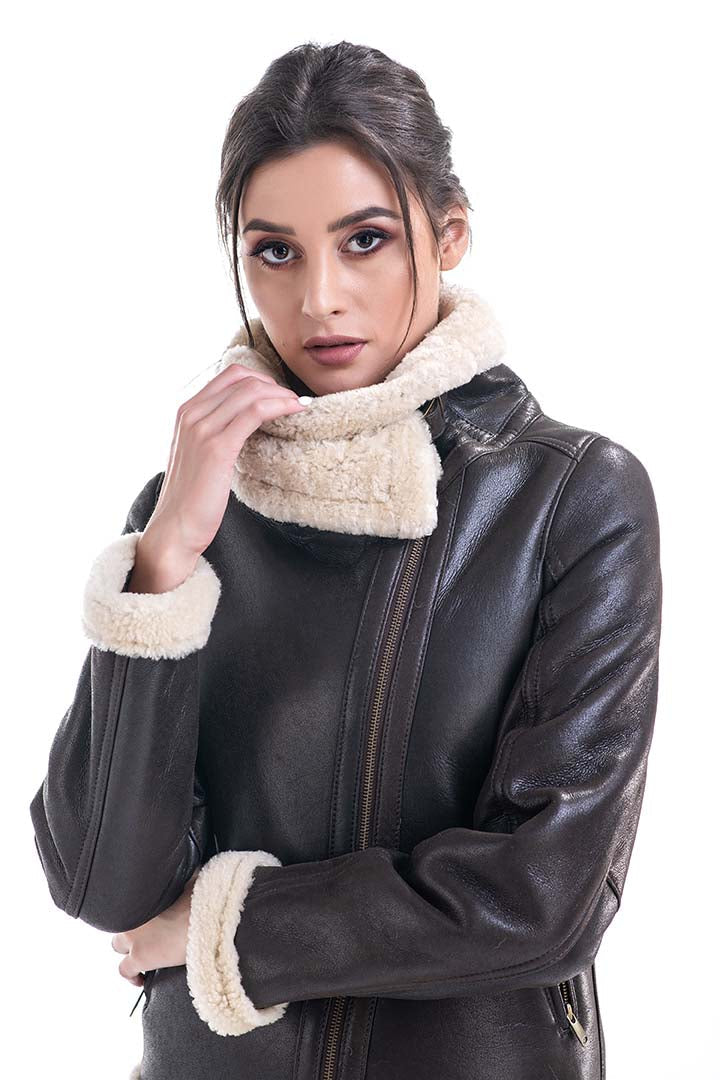 Woman wearing a brown leather jacket with cream fur-lined cuffs and collar on a white background