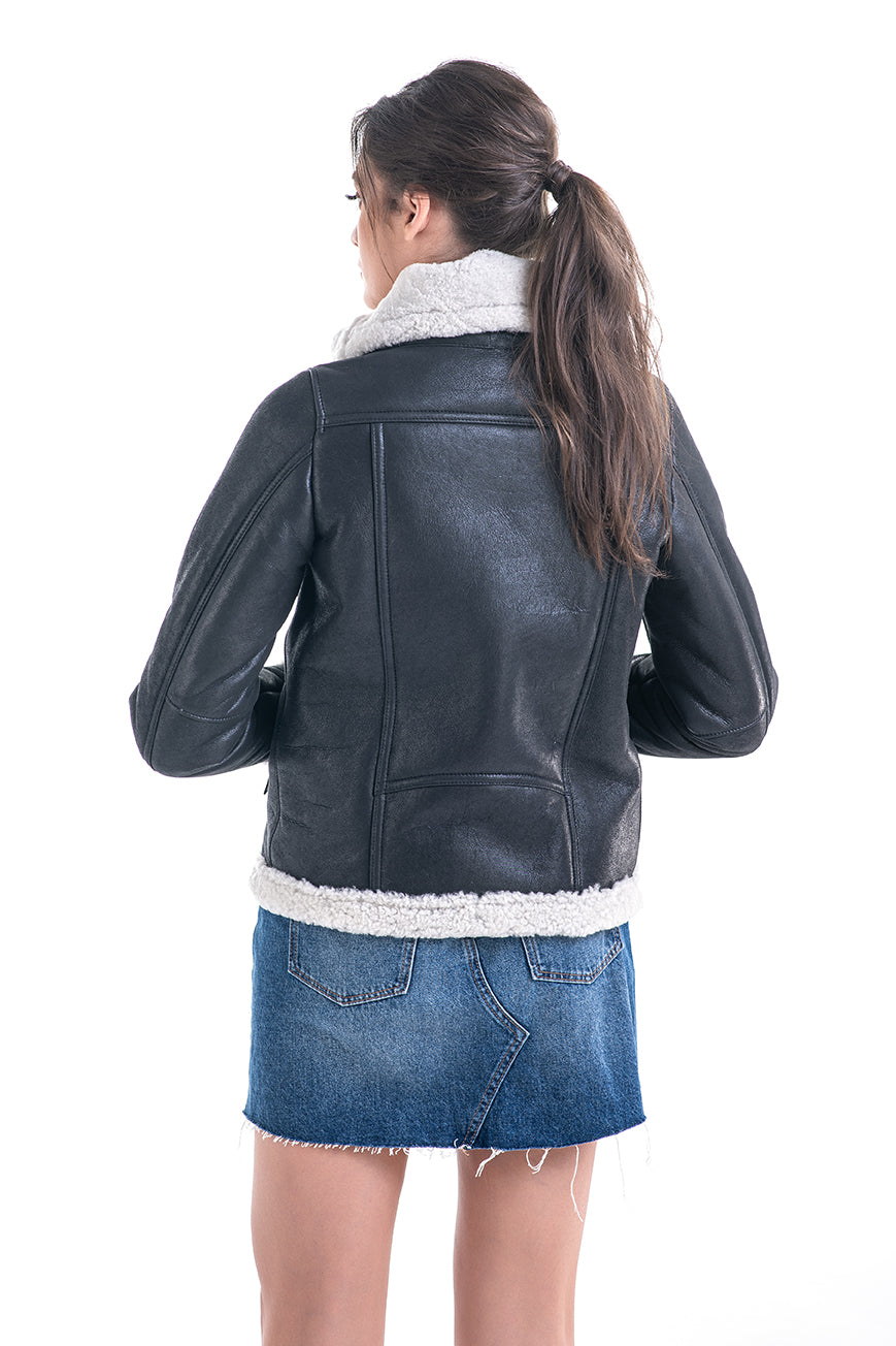 Person wearing a black leather jacket with white lining and a denim skirt on a white background