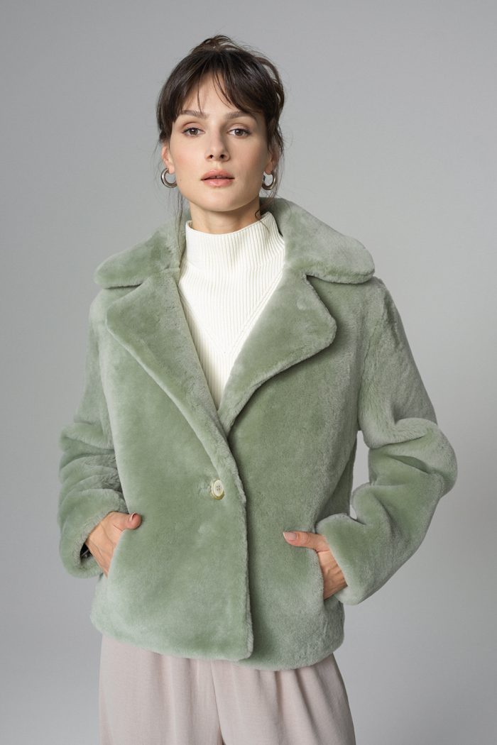Woman wearing a green coat against a gray background