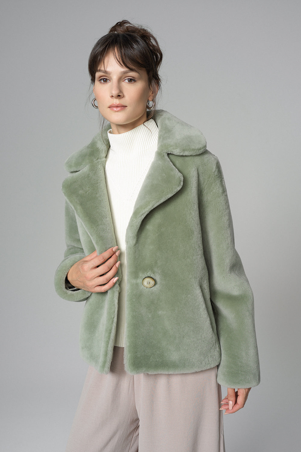 Woman wearing a green coat against a gray background