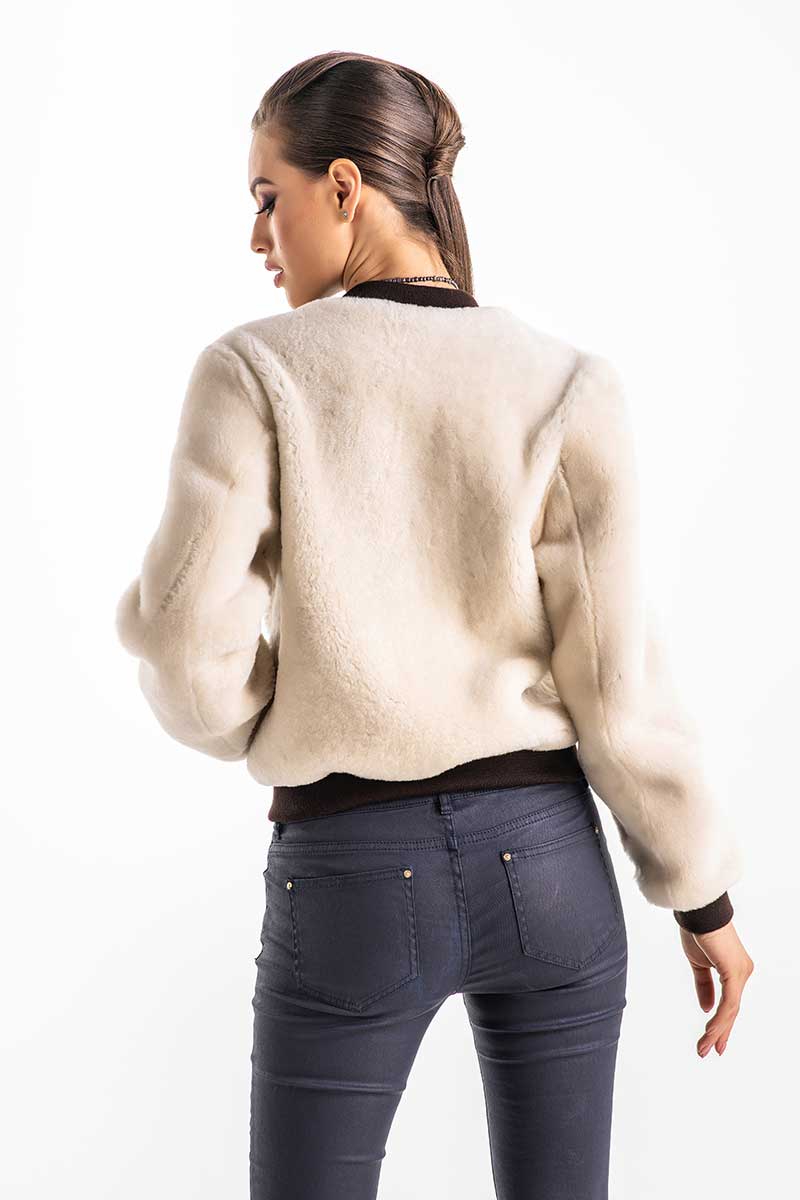 Woman wearing a beige sweater and dark pants on a white background