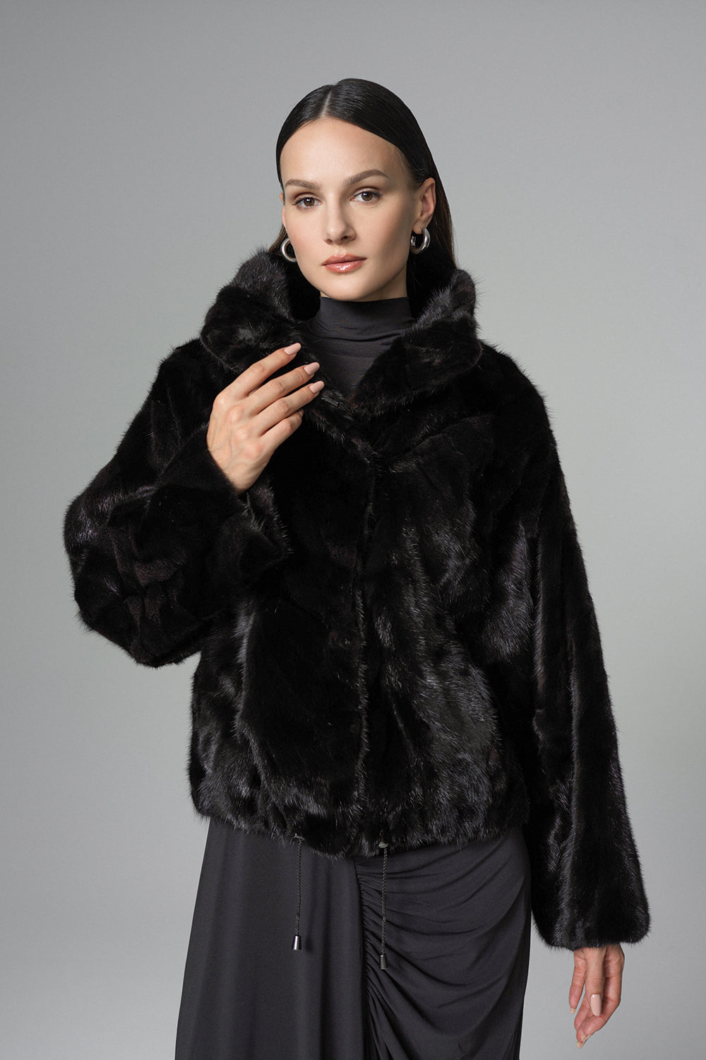 Woman wearing a black fur coat against a gray background