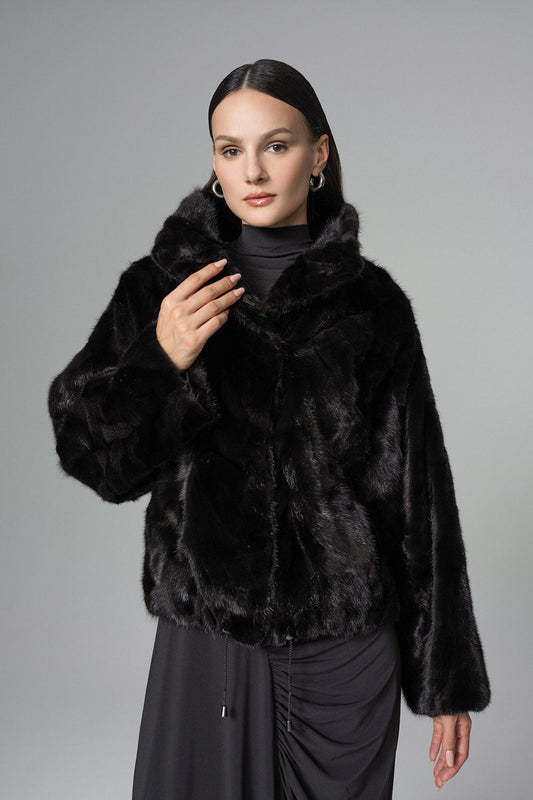Woman wearing a black fur coat against a gray background