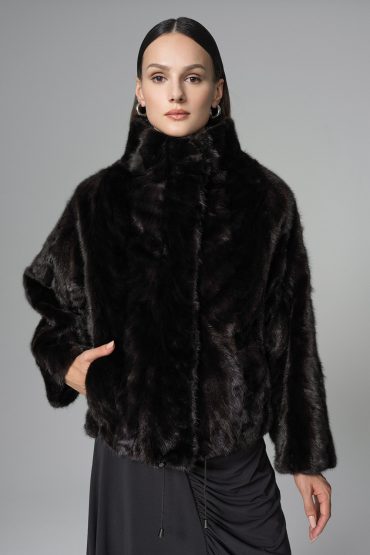 Woman wearing a black fur coat against a gray background