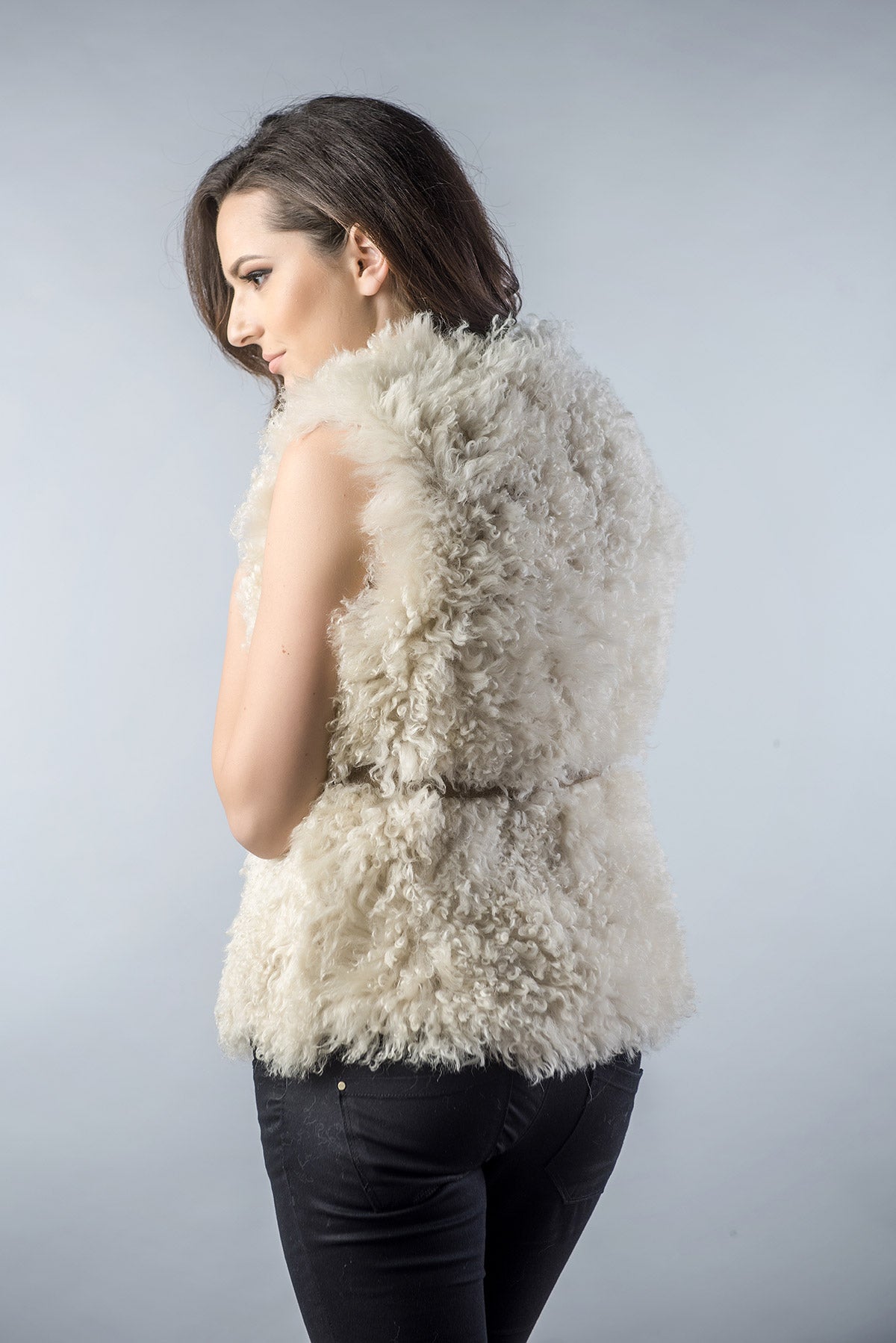 Woman wearing a fluffy white vest against a plain background