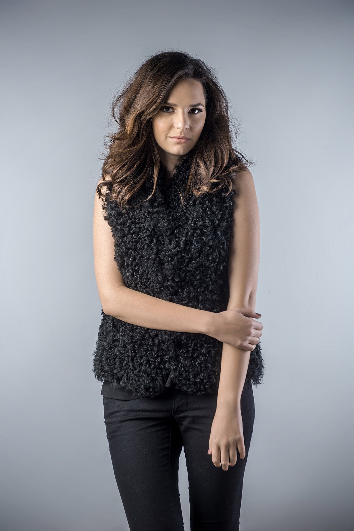 Woman wearing a black textured sleeveless top against a gray background