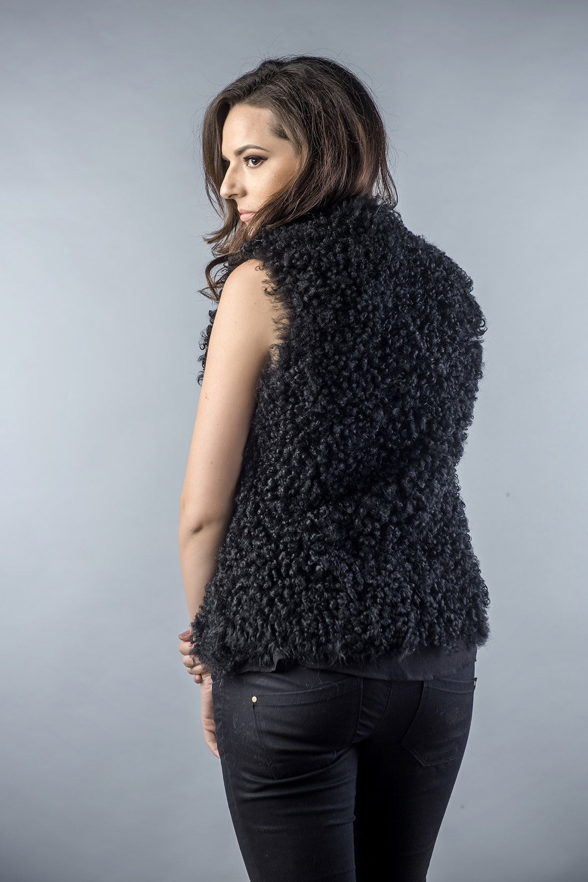 Woman wearing a black textured vest against a gray background
