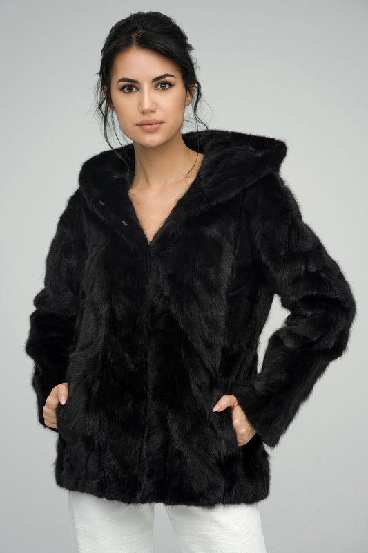 Woman wearing a black fur coat against a gray background