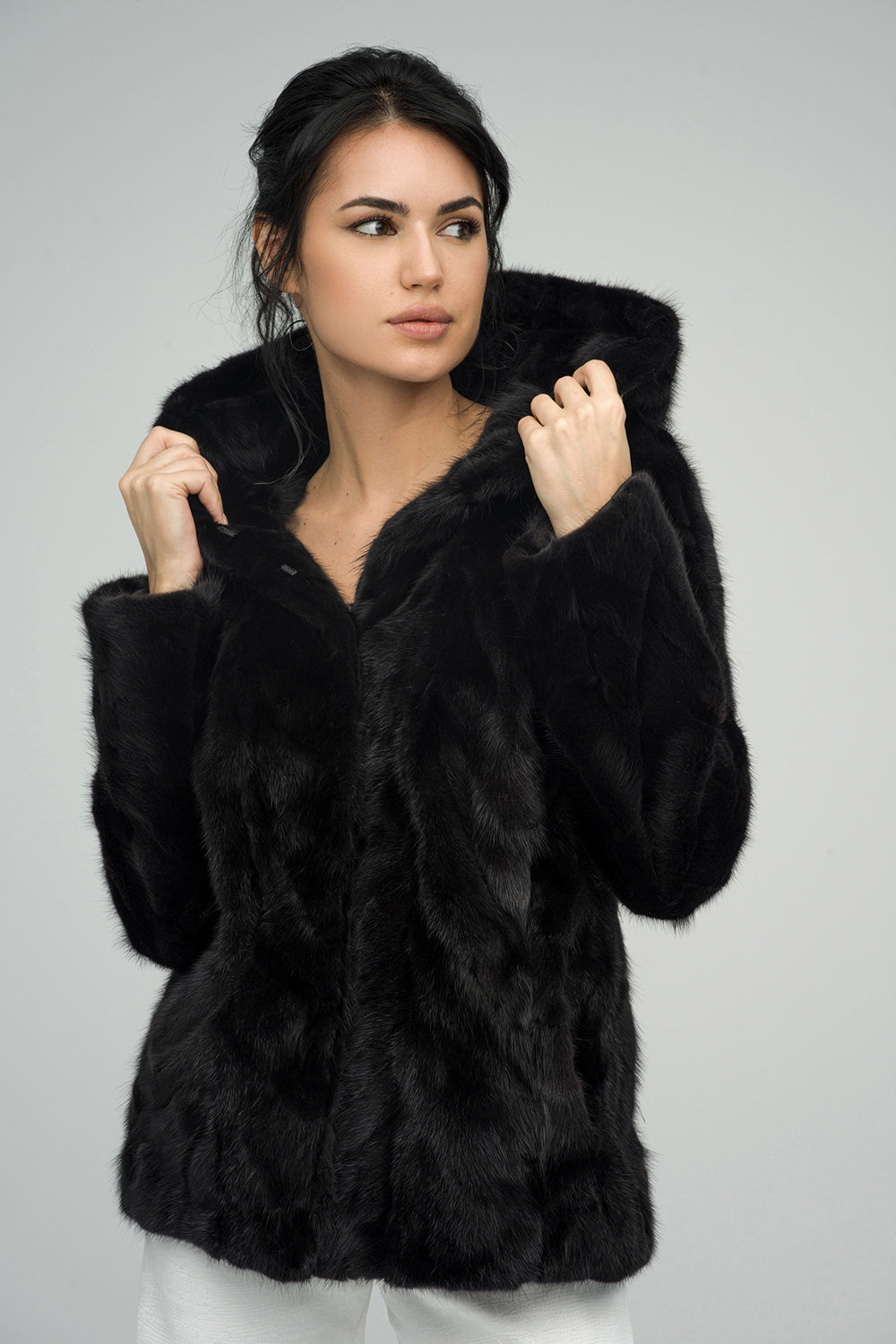Woman wearing a black fur coat against a gray background