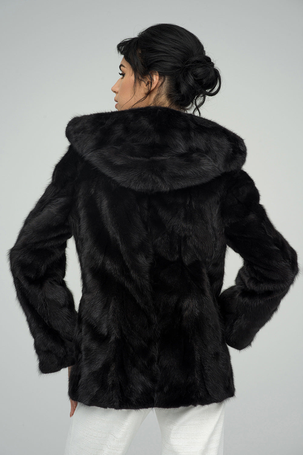Woman wearing a black fur coat against a gray background