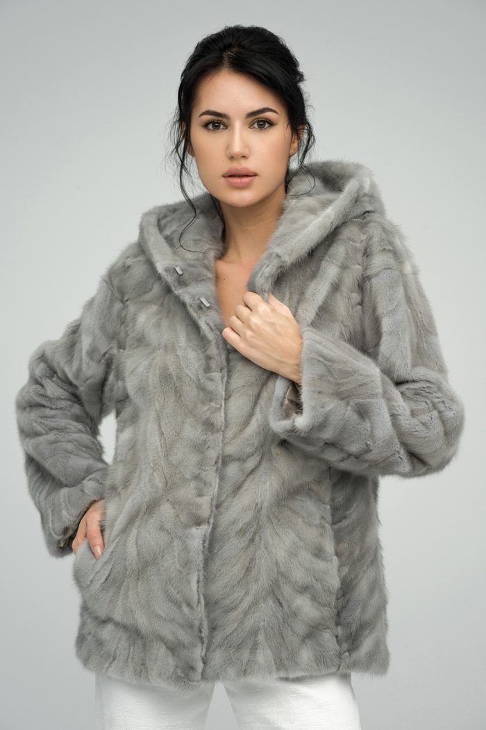 Woman wearing a gray fur coat against a plain background