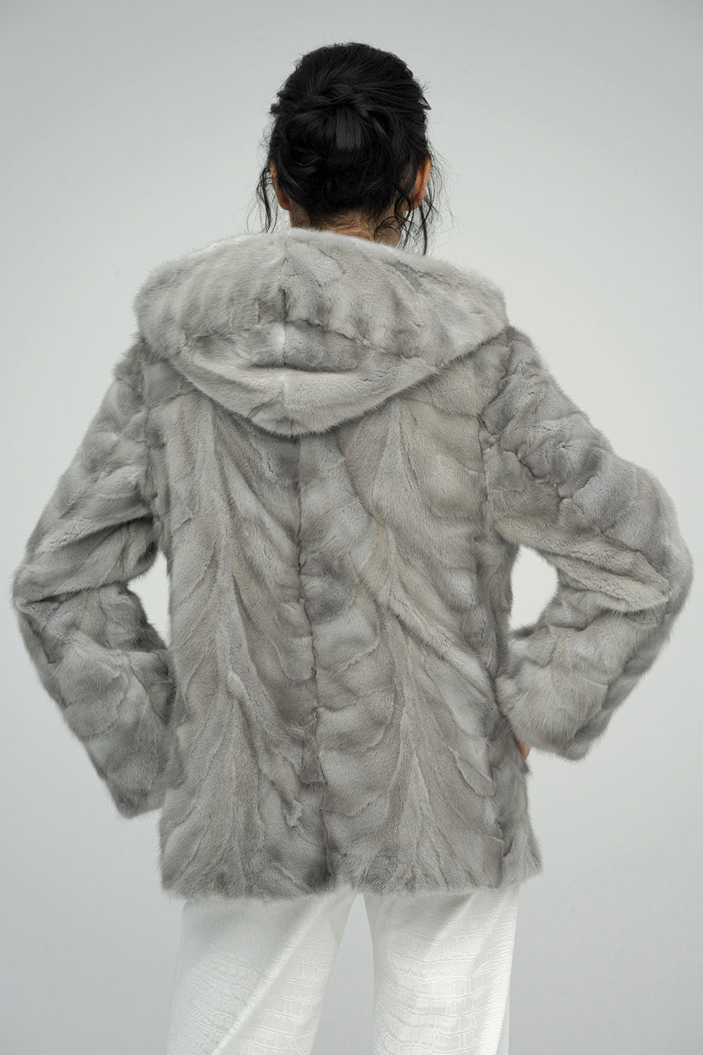 Person wearing a gray fur coat on a plain background