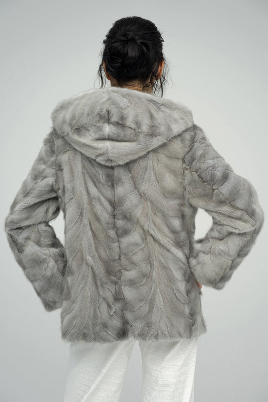 Person wearing a gray fur coat on a plain background