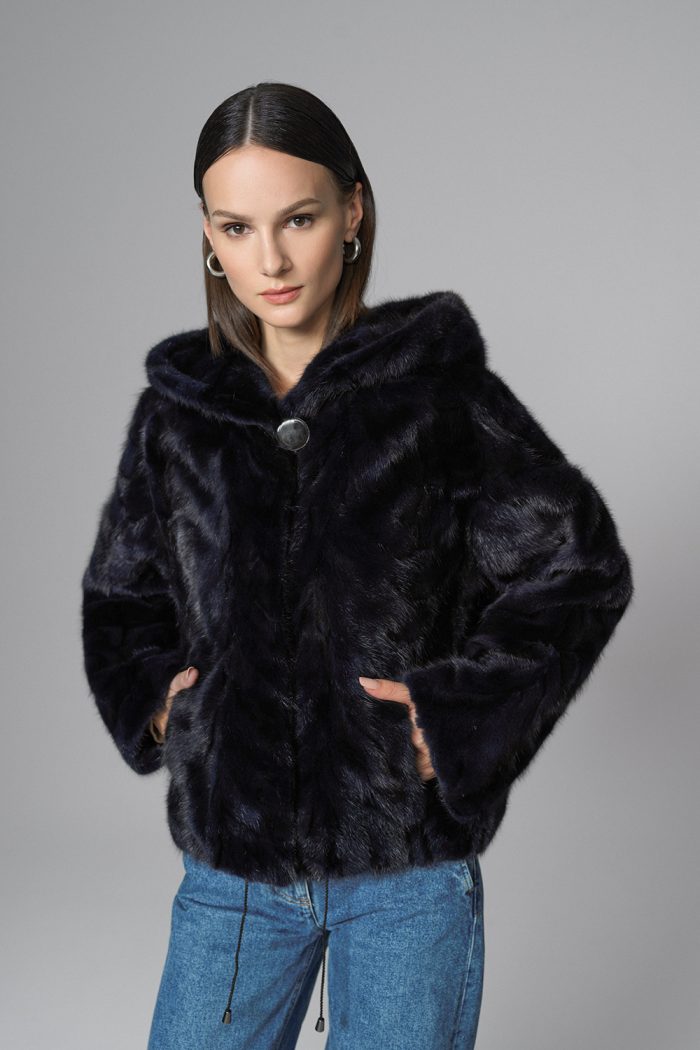 Woman wearing a navy fur coat with a gray background