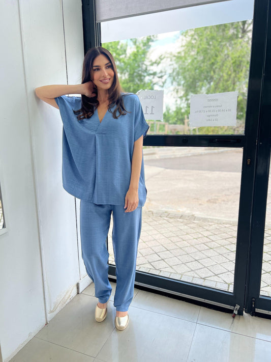 Woman in a blue outfit standing by a glass door.