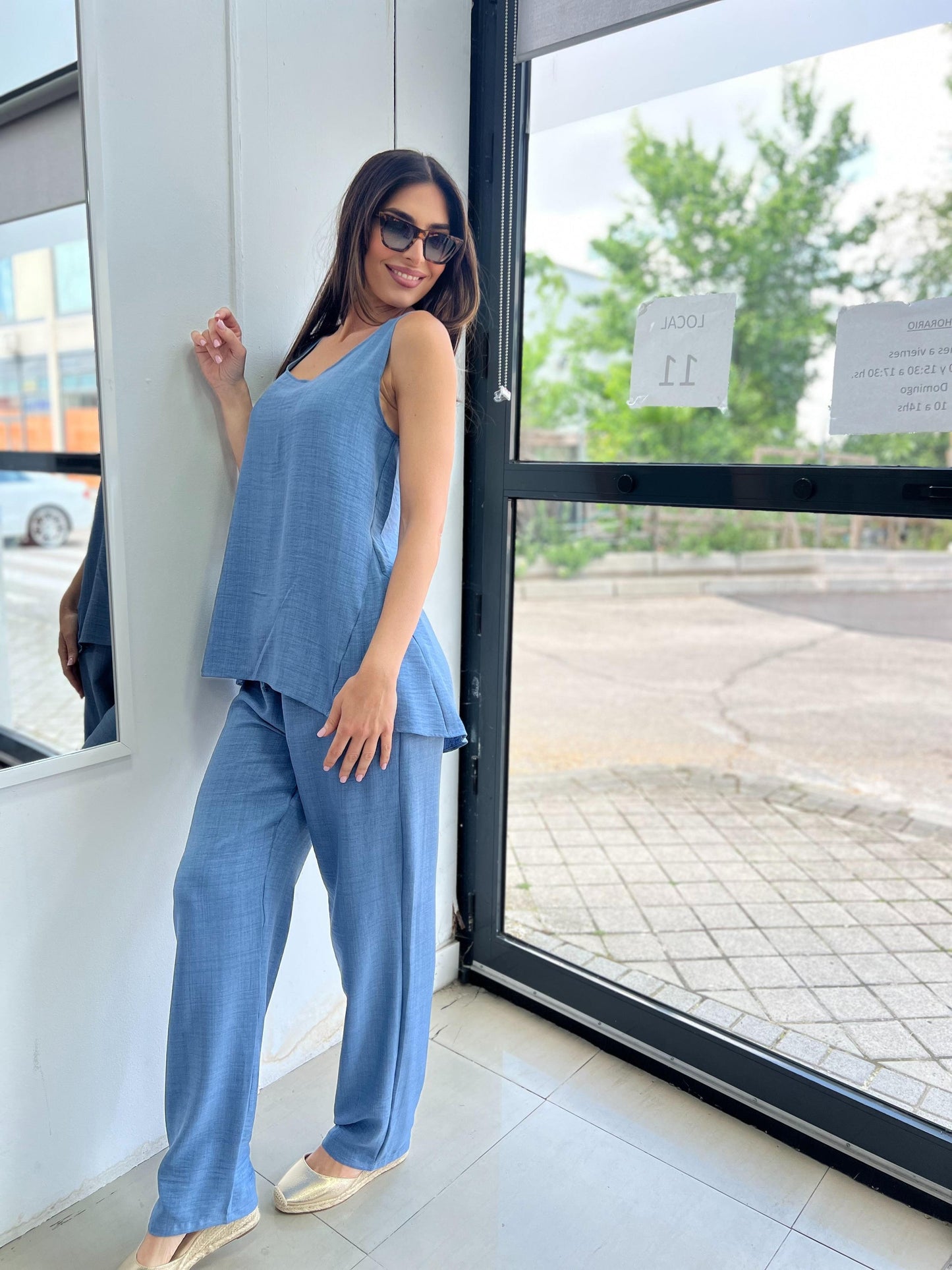 Woman in a blue outfit standing near a glass door.