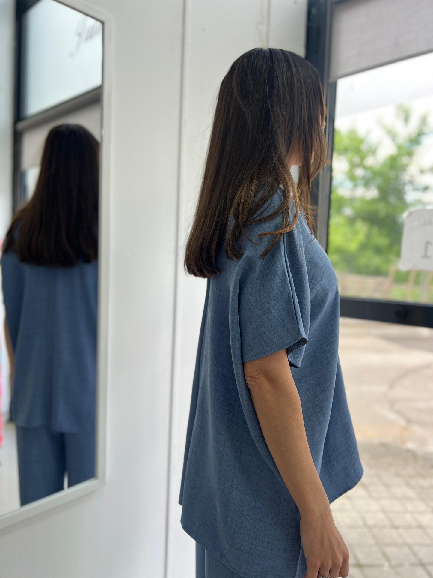 Woman wearing a blue outfit standing in front of a mirror.