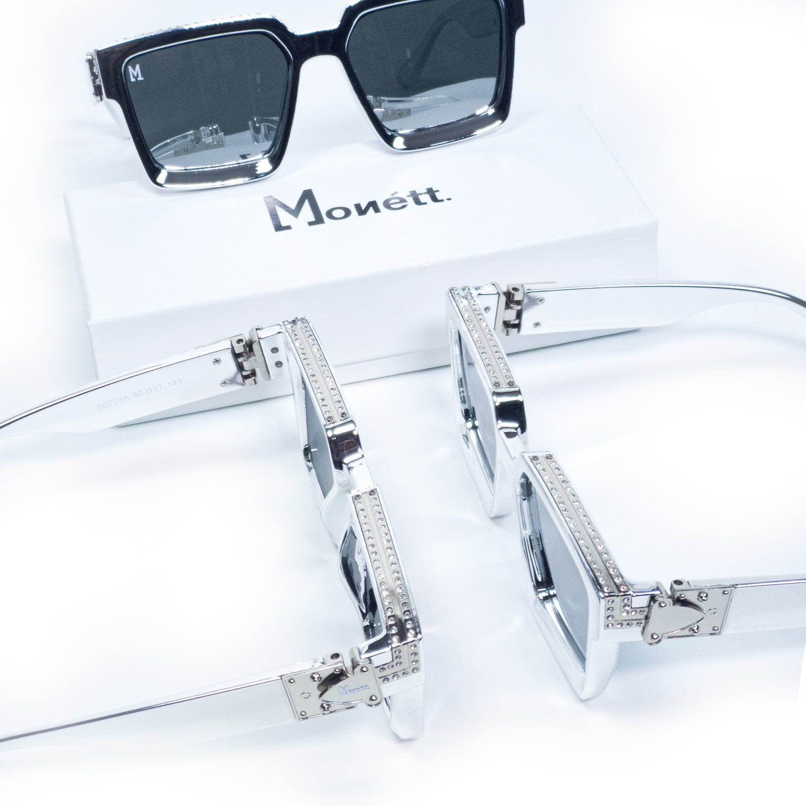Silver sunglasses with decorative elements on a white background, featuring the brand 'Monett'.