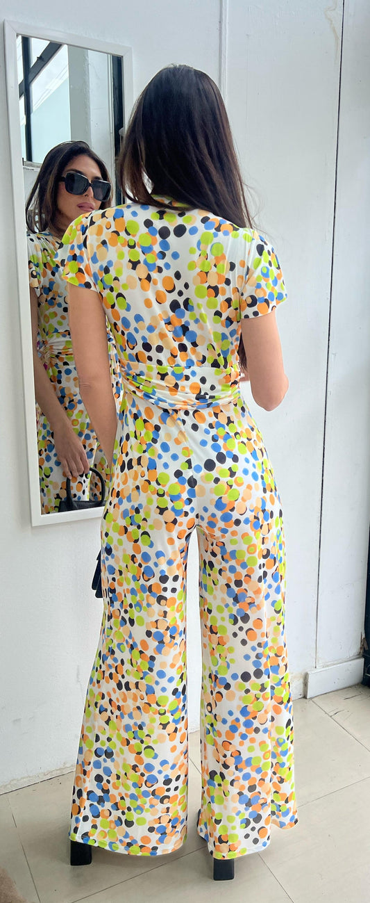 Woman wearing a colorful polka dot jumpsuit looking at herself in the mirror.