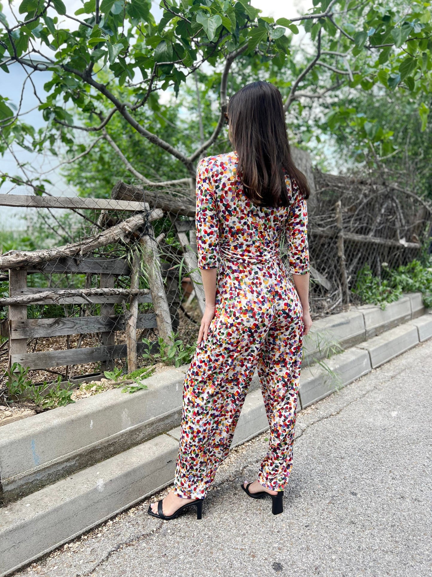 Woman in a colorful floral jumpsuit walking on a path with greenery in the background