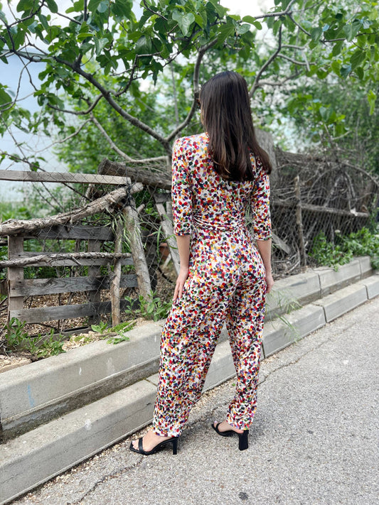 Woman in a colorful floral jumpsuit walking on a path with greenery in the background