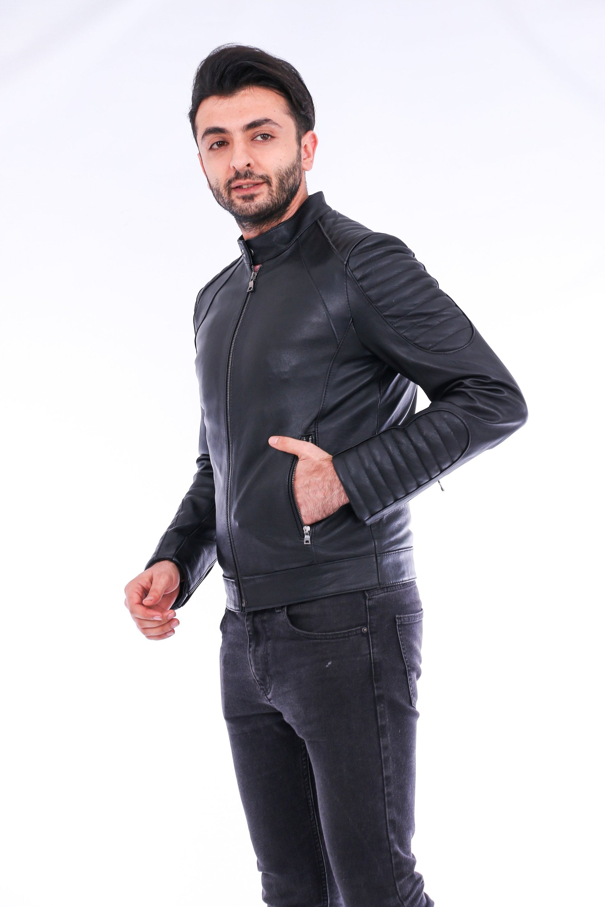 Man wearing a black leather jacket and dark jeans on a white background