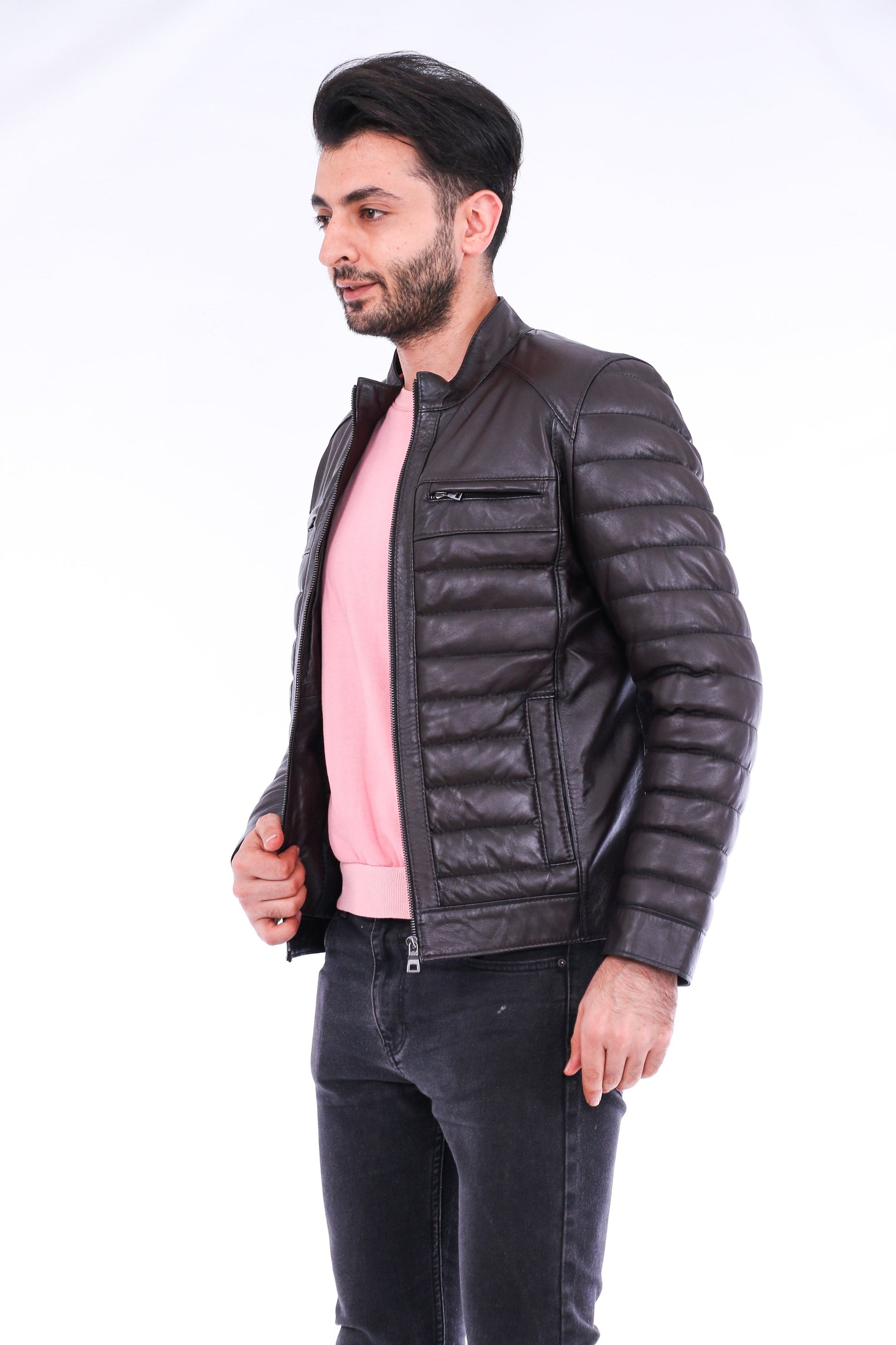 Man wearing a black leather jacket over a pink shirt on a white background