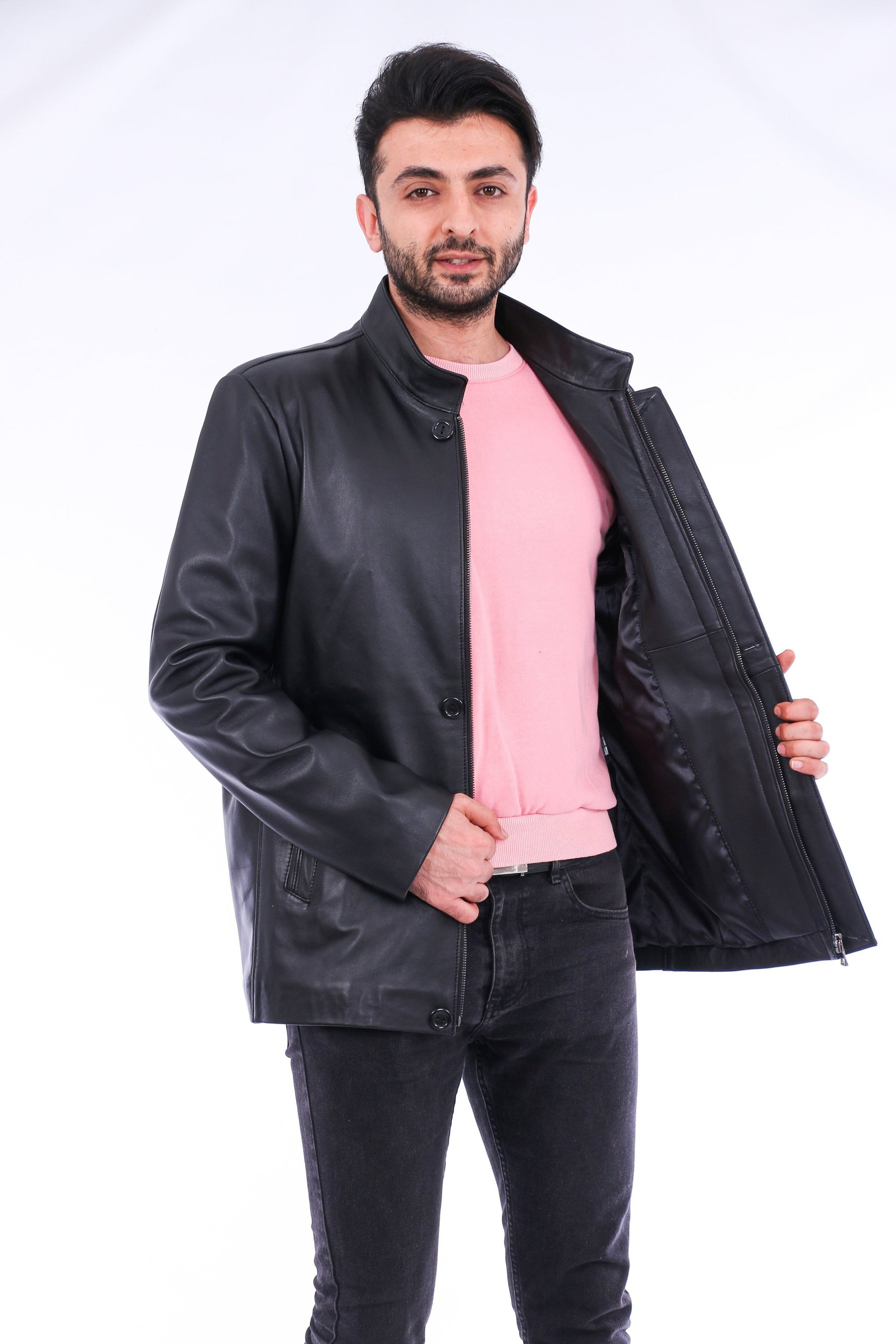 Man wearing a black leather jacket over a pink shirt on a white background