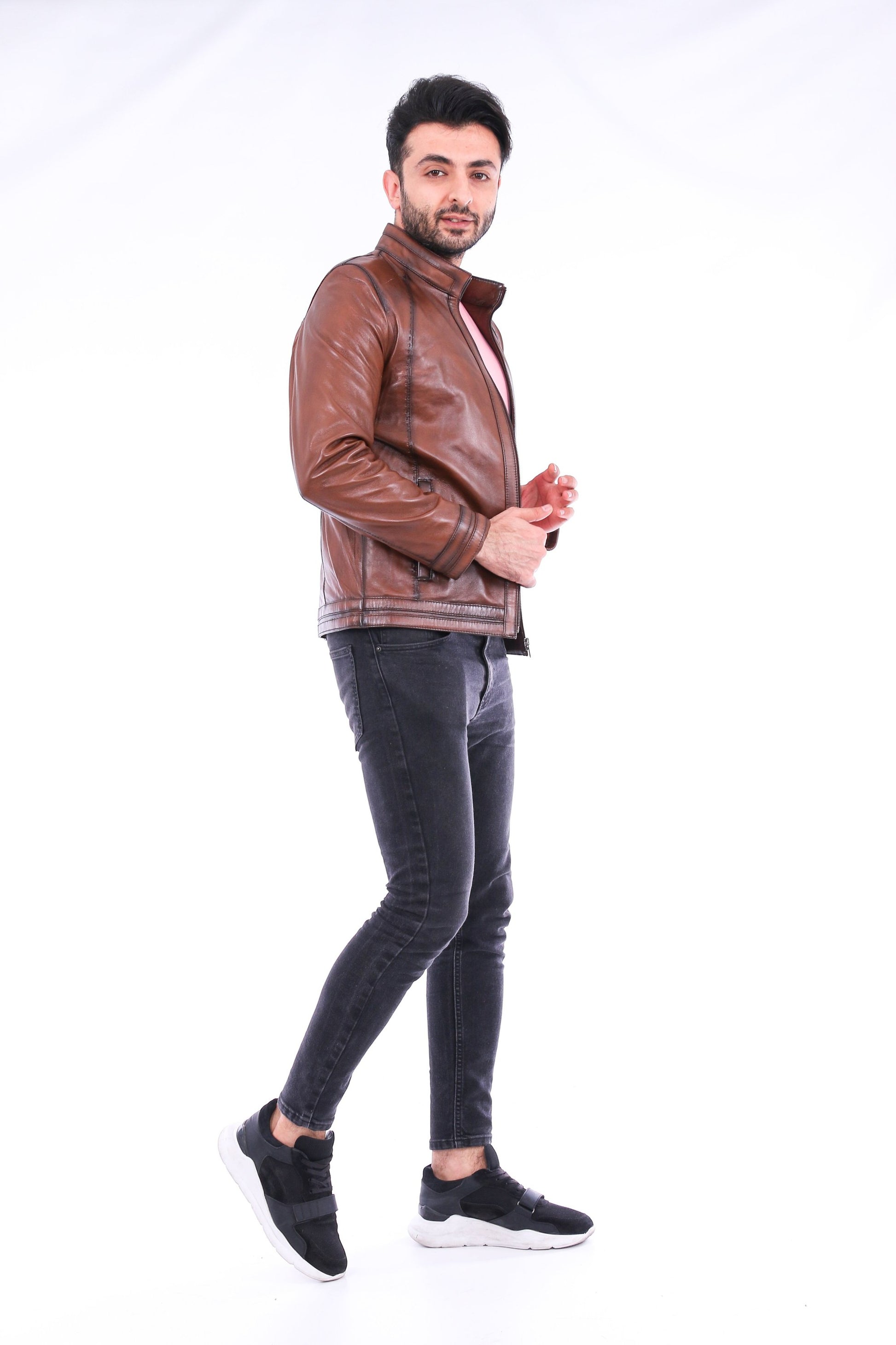 Man wearing a brown leather jacket and black jeans on a white background