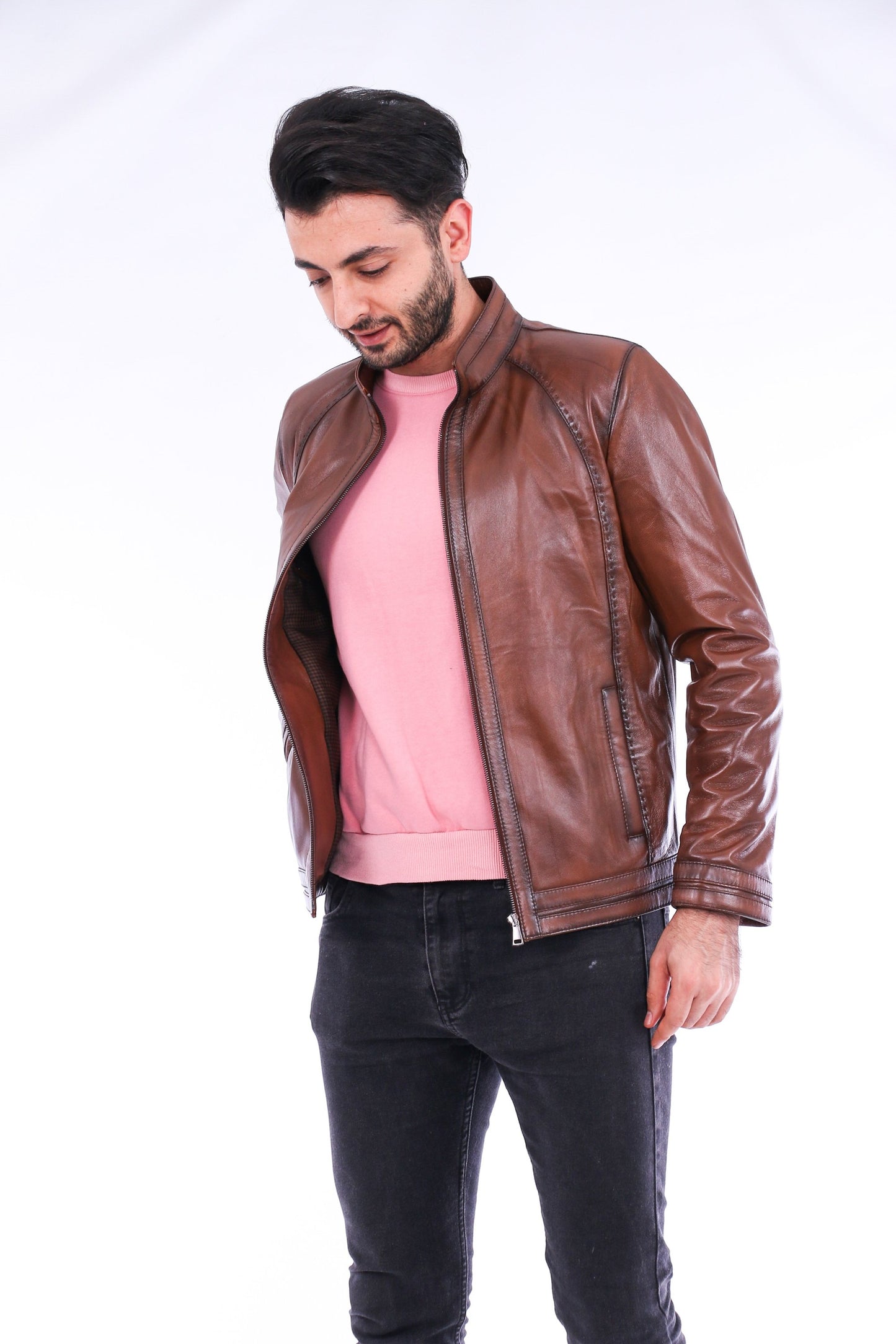 Man wearing a brown leather jacket over a pink shirt on a white background