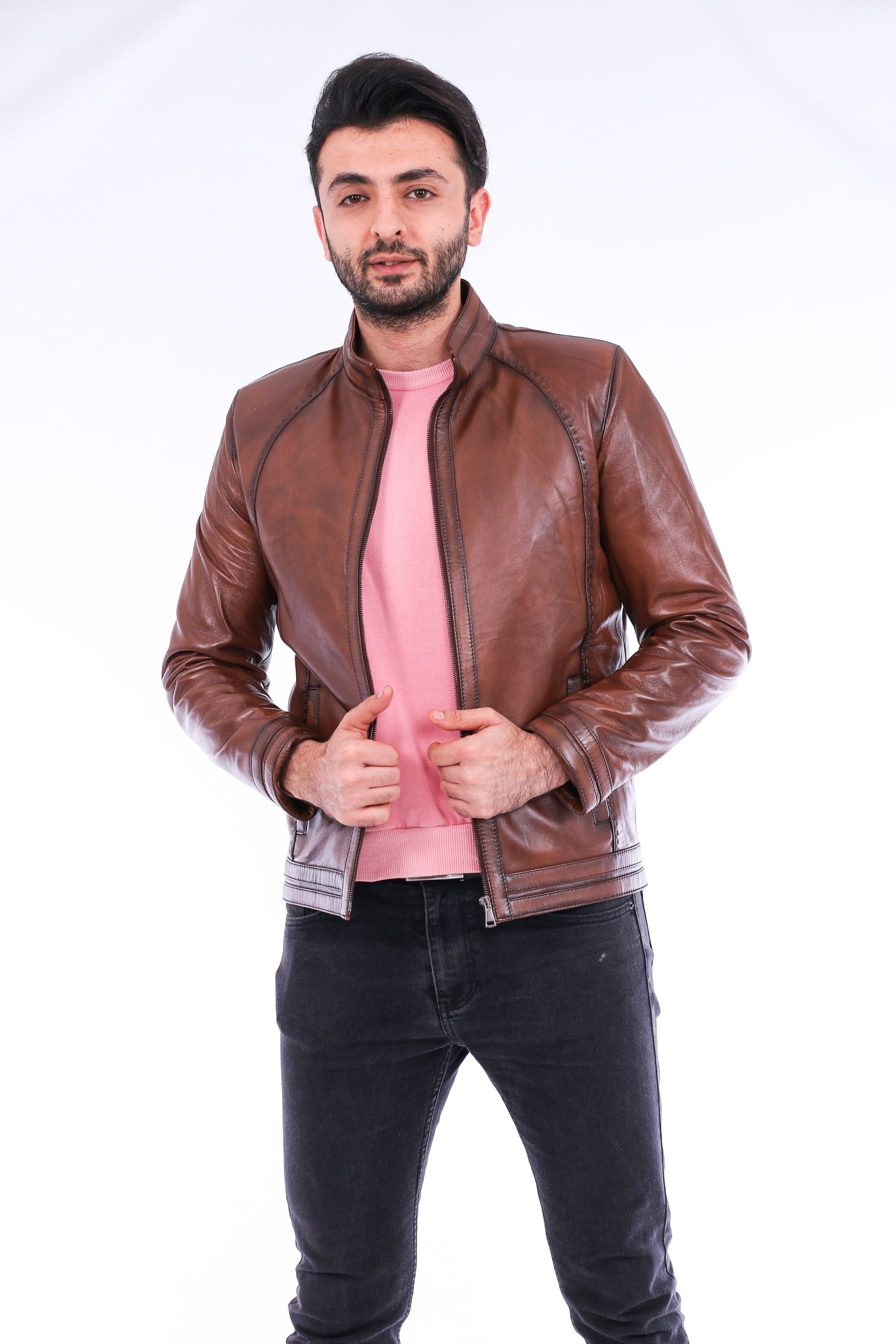 Man wearing a brown leather jacket over a pink shirt on a white background