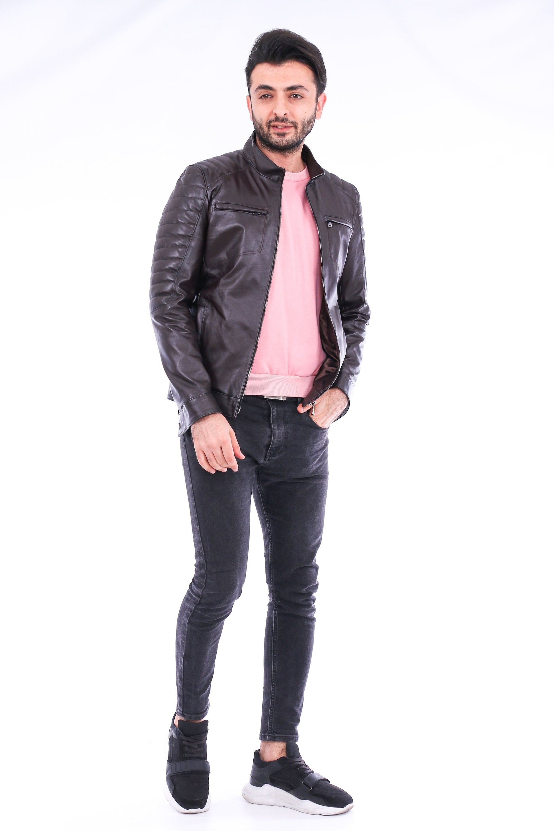 Man wearing a black leather jacket, pink shirt, and black jeans on a white background