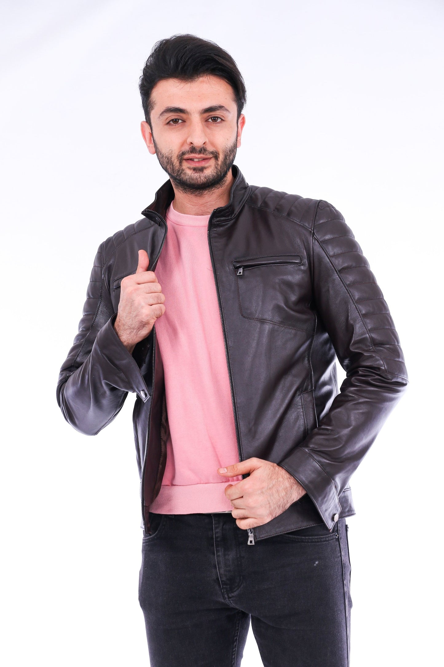 Man wearing a black leather jacket over a pink shirt on a white background
