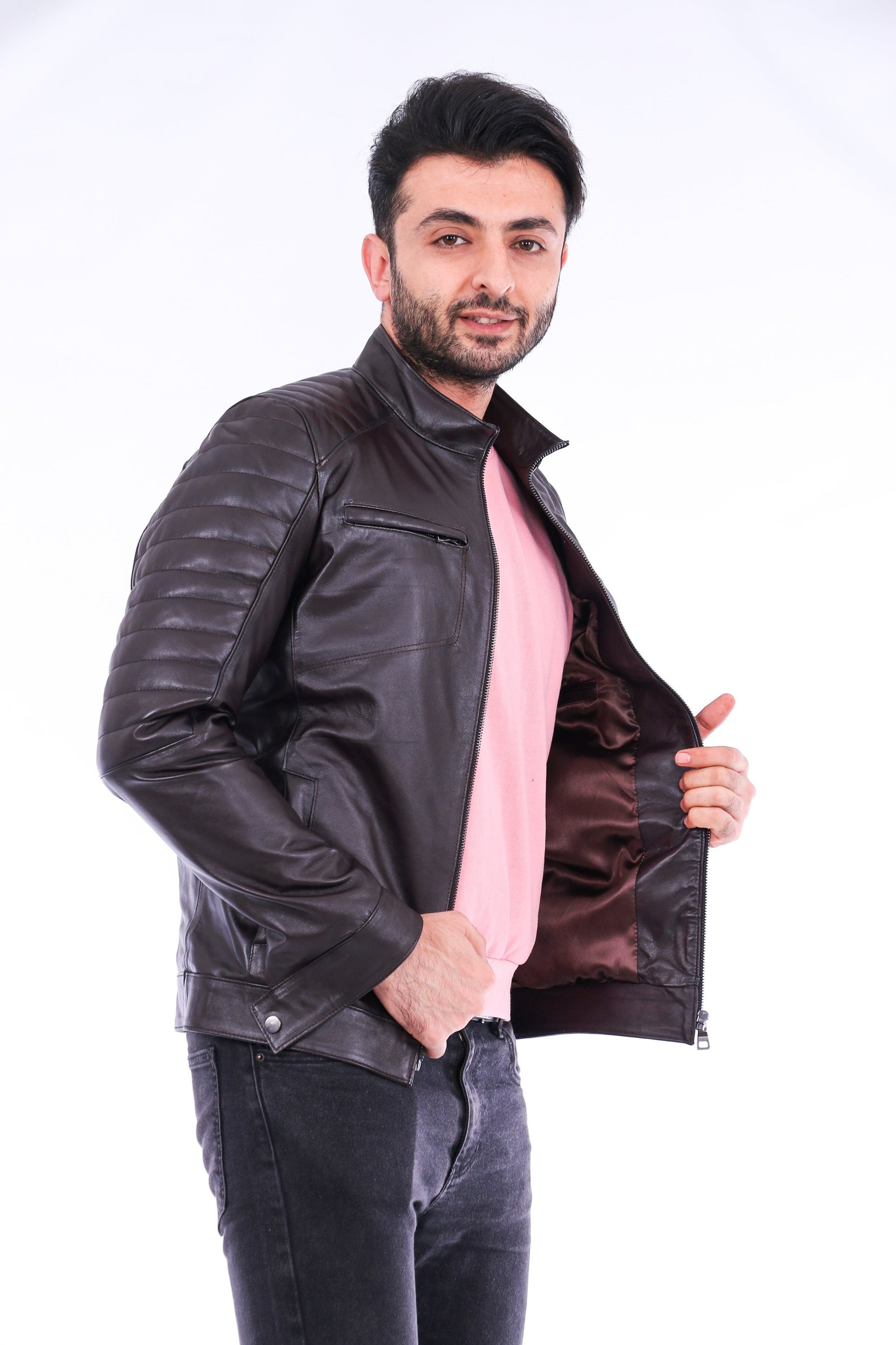 Man wearing a black leather jacket over a pink shirt on a white background