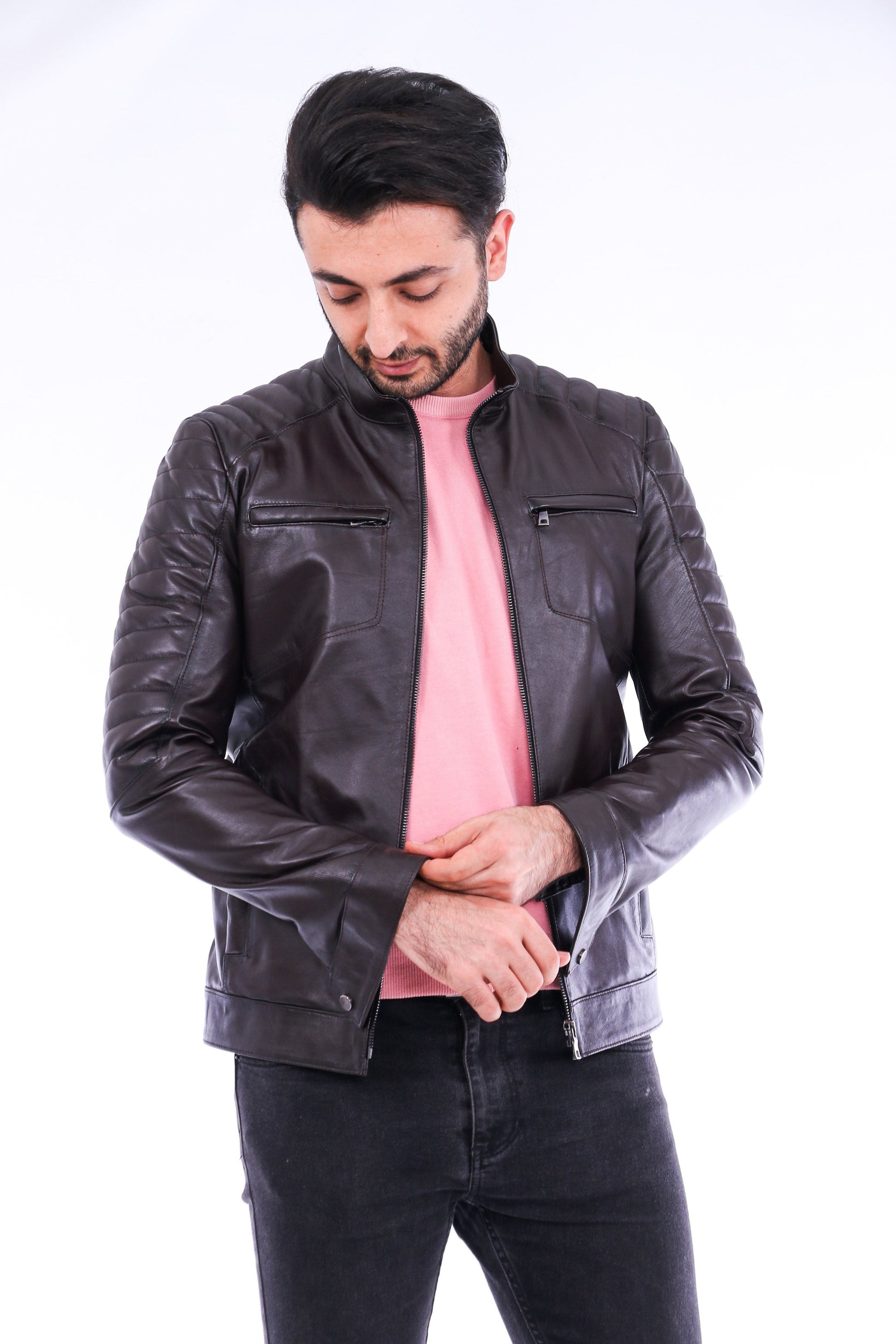 Man wearing a black leather jacket over a pink shirt on a white background