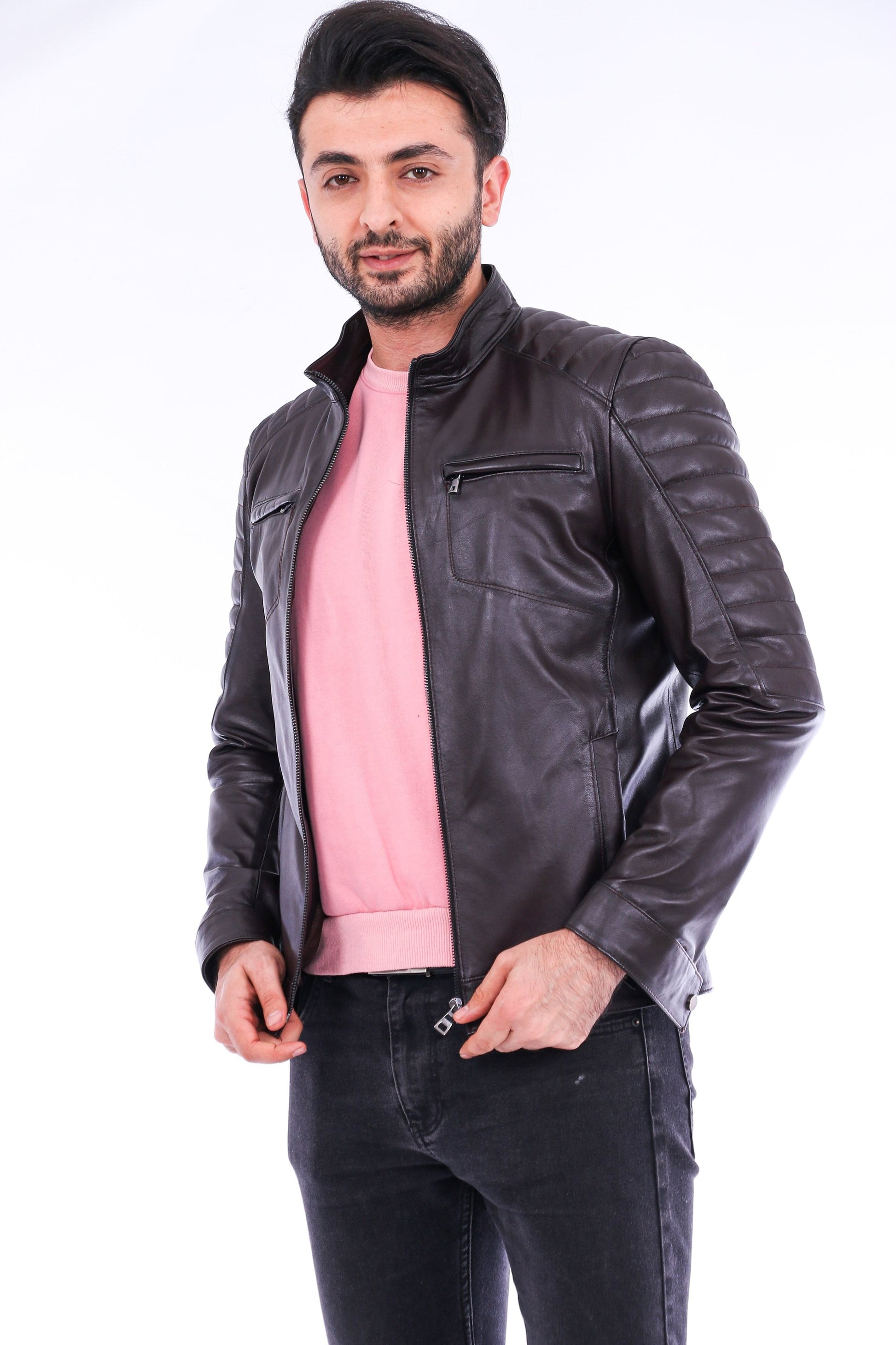 Man wearing a black leather jacket over a pink shirt on a white background