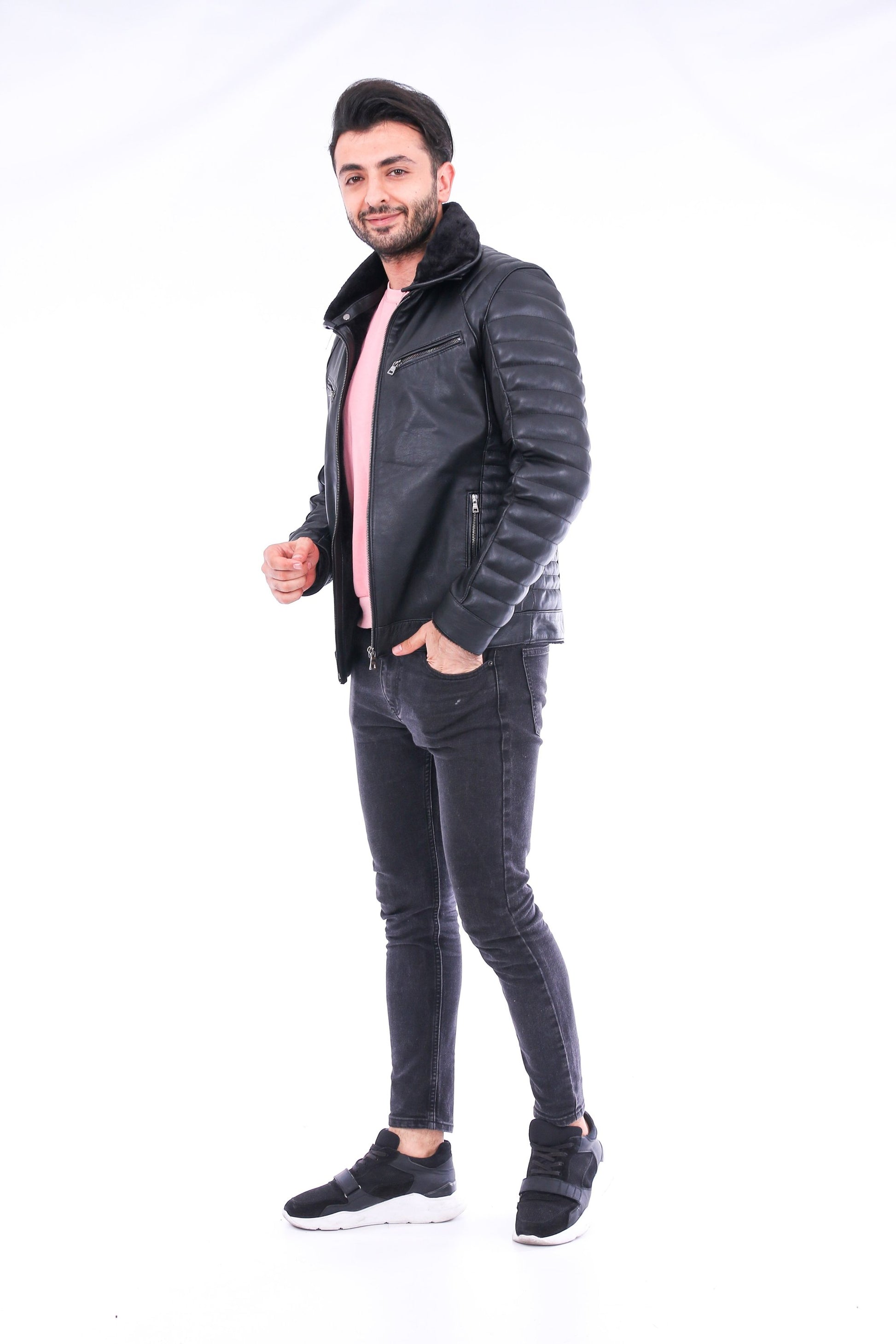 Man wearing a black leather jacket and jeans on a white background