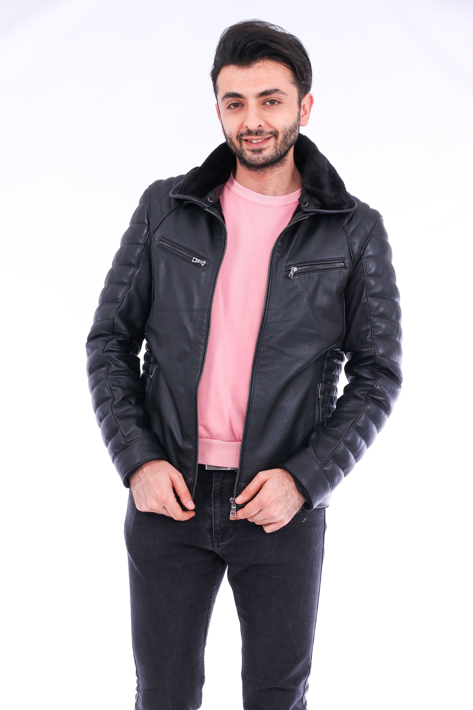 Man wearing a black leather jacket over a pink shirt on a white background