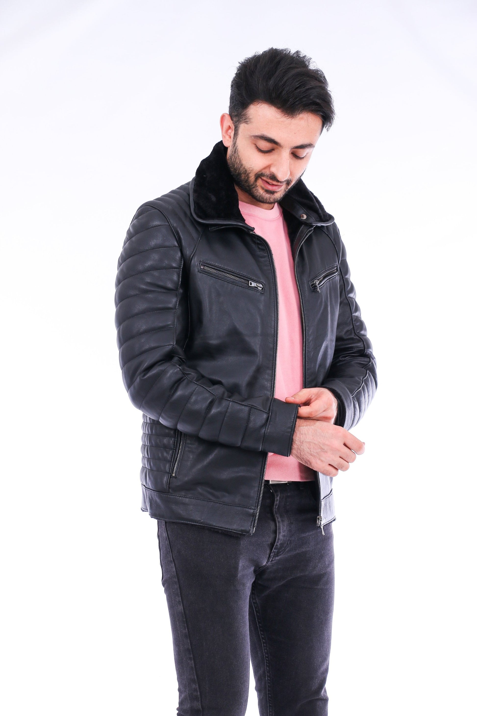 Man wearing a black quilted jacket over a pink shirt on a white background