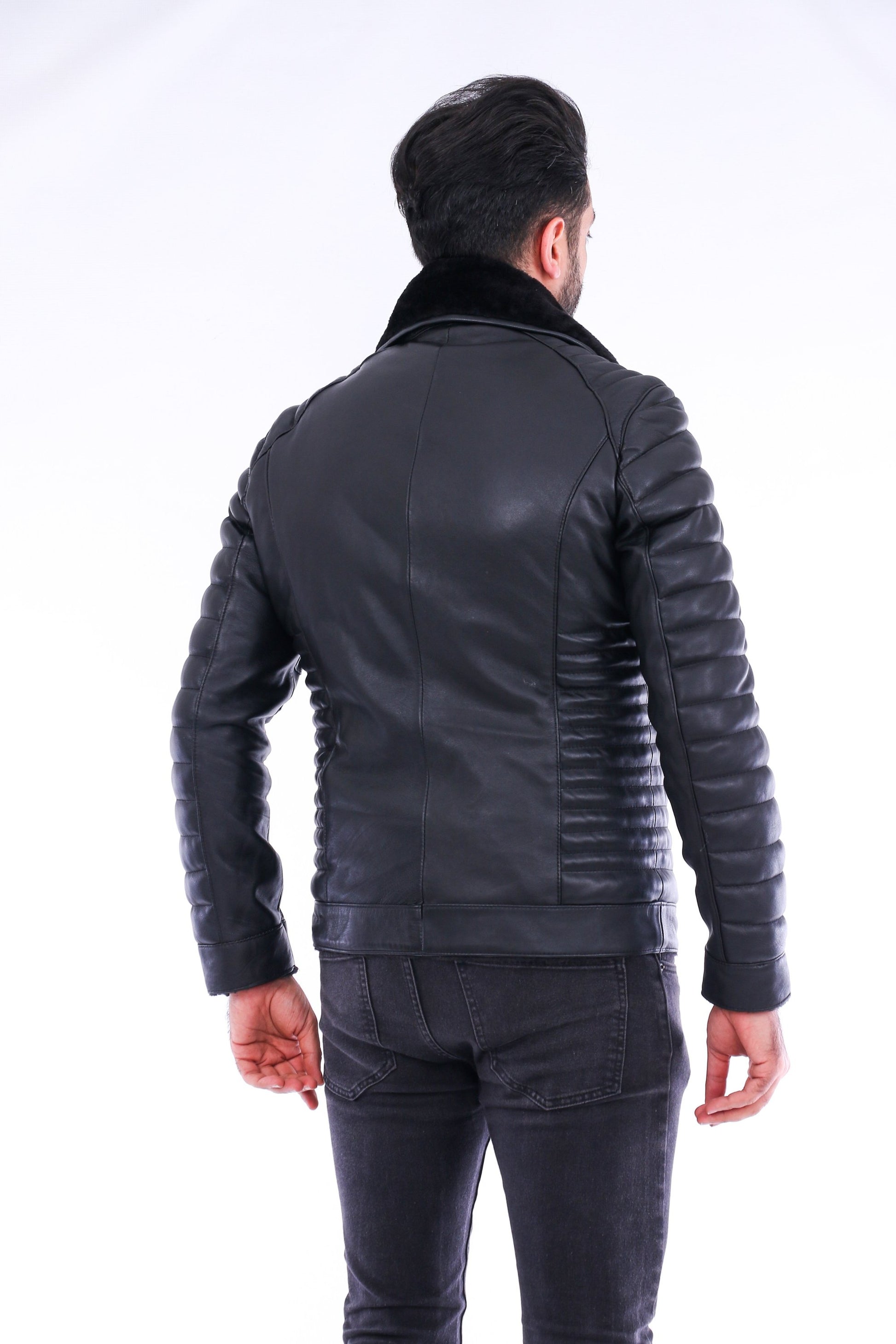 Man wearing a black leather jacket and pants on a white background