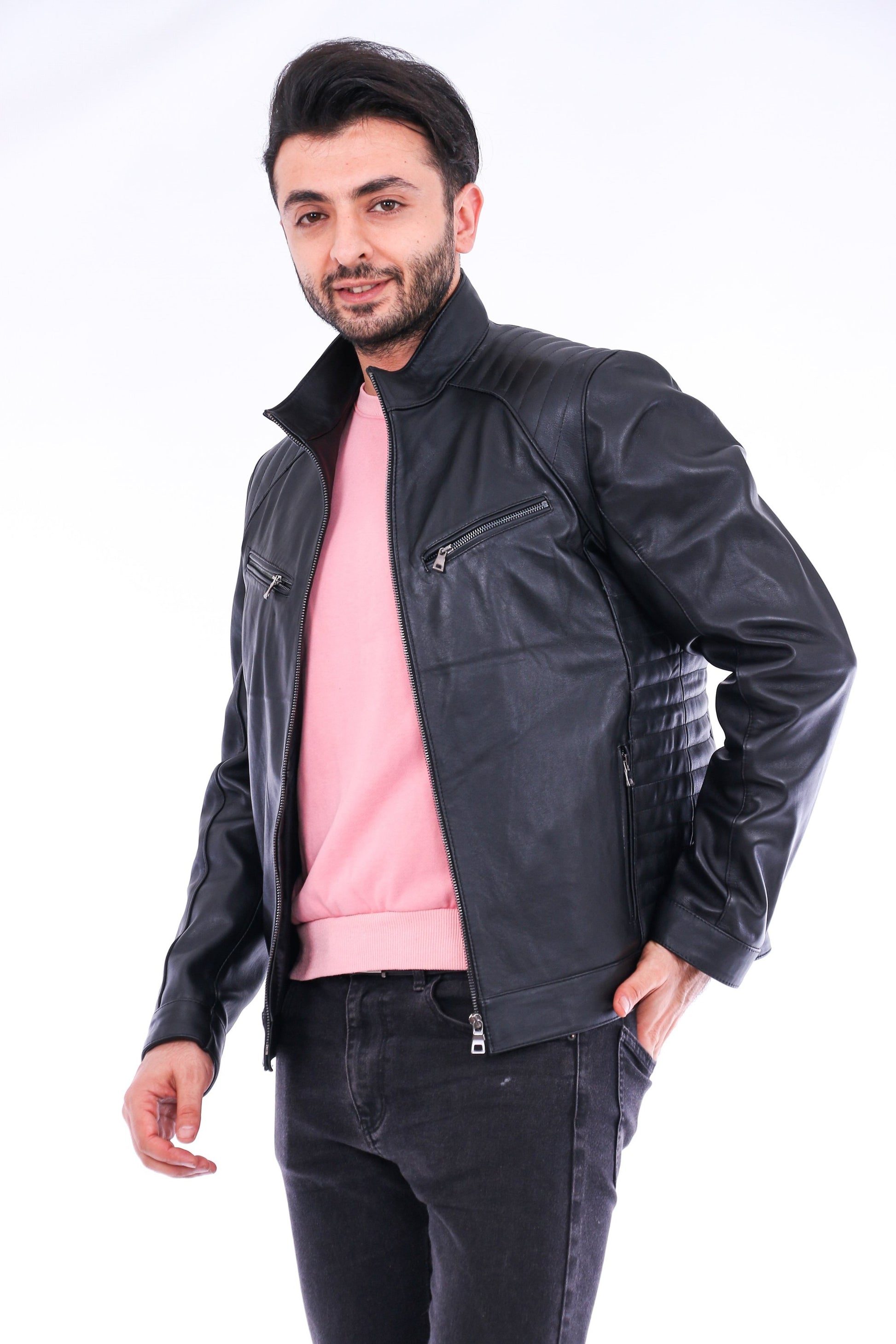 Man wearing a black leather jacket over a pink shirt on a white background