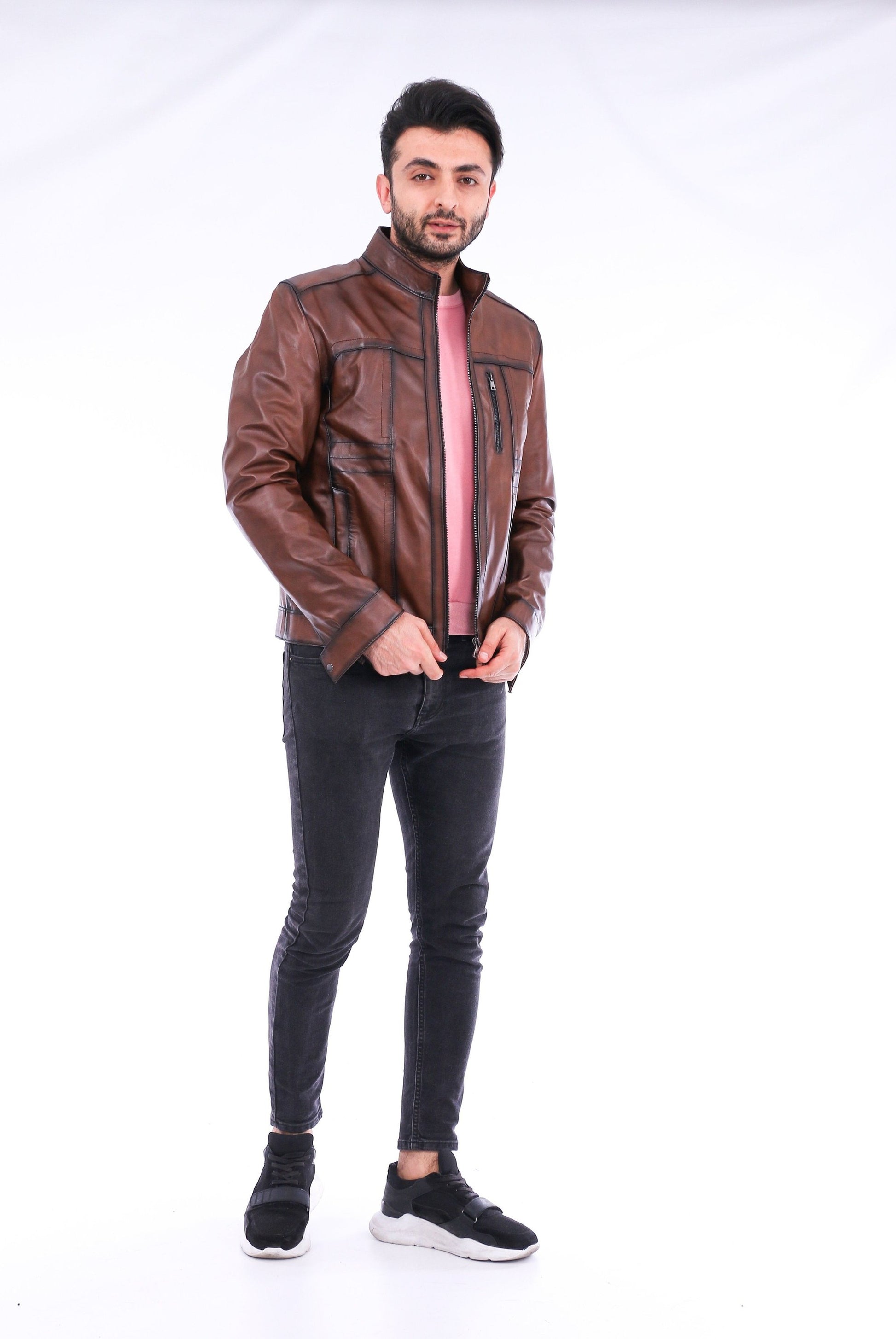 Man wearing a brown leather jacket and black pants on a white background